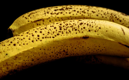 ripe bananas with dark spots on black backgroundの写真素材