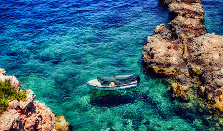 a boat tied to the shorein in crystal clear water, Comino island, Maltaの写真素材