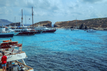 Comino, Malta - July 18, 2019. Tourists crowd at Blue Lagoon to enjoy the clear turquoise water on a sunny summer day with and boats on Comino island, Malta.のeditorial素材