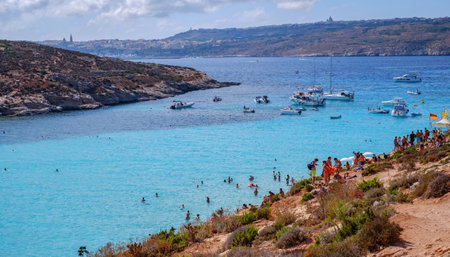 Comino, Malta - July 18, 2019. Tourists crowd at Blue Lagoon to enjoy the clear turquoise water on a sunny summer day with and boats on Comino island, Malta.のeditorial素材