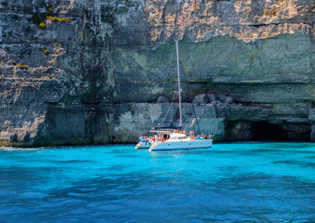 Comino, Malta - July 18, 2019. Tourists crowd at Blue Lagoon to enjoy the clear turquoise water on a sunny summer day with and boats on Comino island, Malta.のeditorial素材