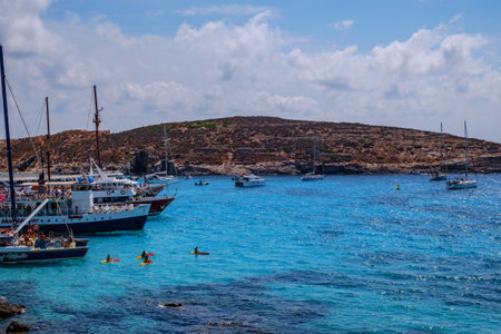 Comino, Malta - July 18, 2019. Tourists crowd at Blue Lagoon to enjoy the clear turquoise water on a sunny summer day with and boats on Comino island, Malta.のeditorial素材