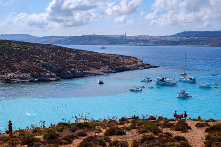 Comino, Malta - July 18, 2019. Tourists crowd at Blue Lagoon to enjoy the clear turquoise water on a sunny summer day with and boats on Comino island, Malta.のeditorial素材