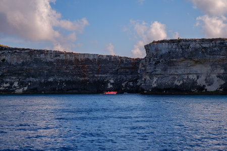 Comino, Malta - July 18, 2019. Tourists crowd at Blue Lagoon to enjoy the clear turquoise water on a sunny summer day with and boats on Comino island, Malta.のeditorial素材