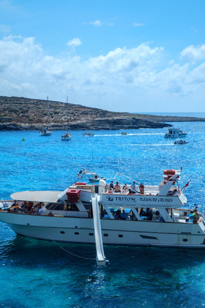Comino, Malta - July 18, 2019. Tourists crowd at Blue Lagoon to enjoy the clear turquoise water on a sunny summer day with and boats on Comino island, Malta.のeditorial素材
