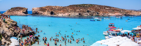 Comino, Malta - July 23, 2019. Tourists crowd at Blue Lagoon to enjoy the clear turquoise water on a sunny summer day with boats on Comino island, Malta.のeditorial素材