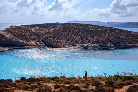 Comino, Malta - July 18, 2019. Tourists crowd at Blue Lagoon to enjoy the clear turquoise water on a sunny summer day with and boats on Comino island, Malta.のeditorial素材