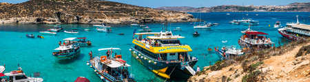 Comino, Malta - July 23, 2019. Tourists crowd at Blue Lagoon to enjoy the clear turquoise water on a sunny summer day with boats on Comino island, Malta.のeditorial素材