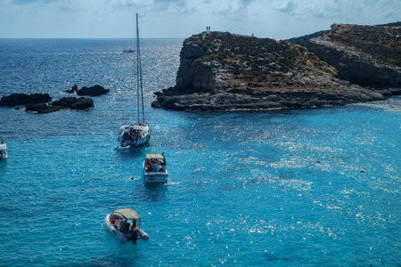 Comino, Malta - July 18, 2019. Tourists crowd at Blue Lagoon to enjoy the clear turquoise water on a sunny summer day with and boats on Comino island, Malta.のeditorial素材