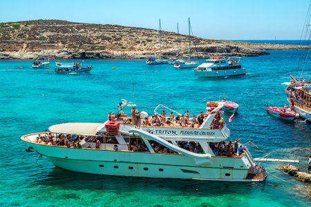 Comino, Malta - July 23, 2019. Tourists crowd at Blue Lagoon to enjoy the clear turquoise water on a sunny summer day with boats on Comino island, Malta.のeditorial素材