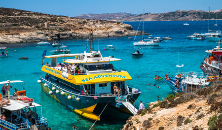 Comino, Malta - July 23, 2019. Tourists crowd at Blue Lagoon to enjoy the clear turquoise water on a sunny summer day with boats on Comino island, Malta.のeditorial素材