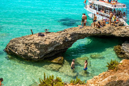 Comino, Malta - July 23, 2019. Tourists crowd at Blue Lagoon to enjoy the clear turquoise water on a sunny summer day with boats on Comino island, Malta.のeditorial素材