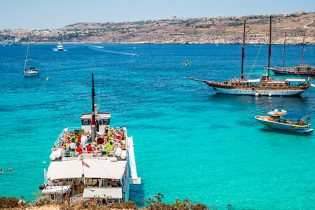 Comino, Malta - July 23, 2019. Tourists crowd at Blue Lagoon to enjoy the clear turquoise water on a sunny summer day with boats on Comino island, Malta.のeditorial素材