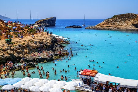 Comino, Malta - July 23, 2019. Tourists crowd at Blue Lagoon to enjoy the clear turquoise water on a sunny summer day with boats on Comino island, Malta.のeditorial素材