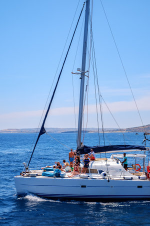 Comino, Malta - July 18, 2019. Tourists crowd at Blue Lagoon to enjoy the clear turquoise water on a sunny summer day with and boats on Comino island, Malta.のeditorial素材