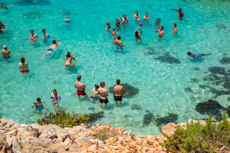 Comino, Malta - July 23, 2019. Tourists crowd at Blue Lagoon to enjoy the clear turquoise water on a sunny summer day with boats on Comino island, Malta.のeditorial素材