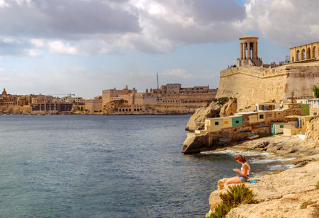 Valletta city, Malta - July 16, 2019. A girl on the rocks near the Wuestenwinds beach in Valletta, Maltaのeditorial素材