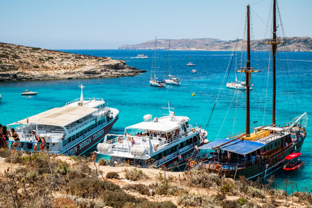Comino, Malta - July 23, 2019. Tourists crowd at Blue Lagoon to enjoy the clear turquoise water on a sunny summer day with boats on Comino island, Malta.のeditorial素材