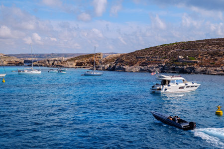 Comino, Malta - July 18, 2019. Tourists crowd at Blue Lagoon to enjoy the clear turquoise water on a sunny summer day with and boats on Comino island, Malta.のeditorial素材