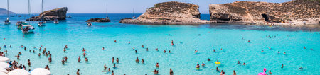 Comino, Malta - July 23, 2019. Tourists crowd at Blue Lagoon to enjoy the clear turquoise water on a sunny summer day with boats on Comino island, Malta.のeditorial素材