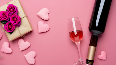 Top view of Valentines Day gift with wine and pink rose bouquet on pink background design conceptの素材