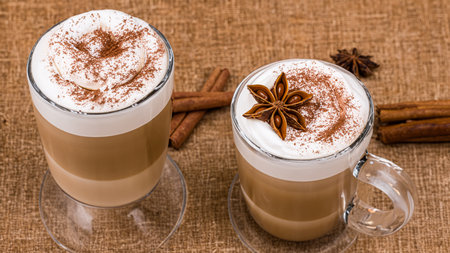 caffe latte with whipped cream, cinnamon and anise in a glassの素材