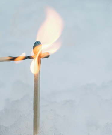 burning wooden matchsticks with hot fire flame on snow backgroundの写真素材