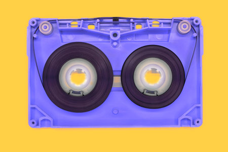 blue old audio cassette tape open on yellow backgroundの写真素材