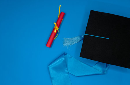 Graduation cap with diploma on blue backgroundの写真素材