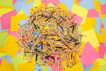 matchsticks of various shapes and colors with multicolored paper sticky notes on background
