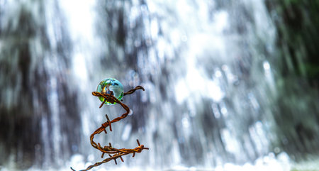 The concept of symbolism. On a waterfall in the background is a glass globe reflecting the forest in...