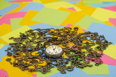The concept of symbolism. Antique rotten pocket watch with Bronze ornamental keys on a background of multicolored paper sticky notesの写真素材