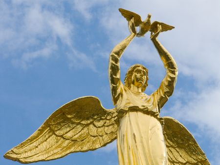 Sculpture of golden angel with pigeon in handsの写真素材