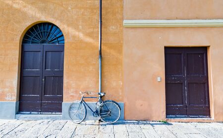 A bicycle leaning against the wall between two doors