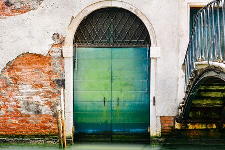 A door of a building along a canal in Venice, Italyの写真素材