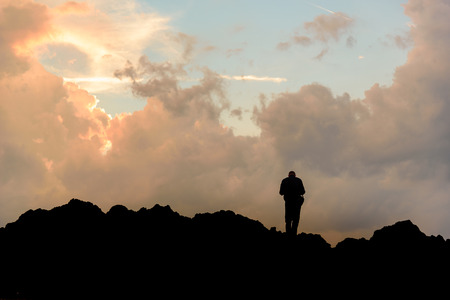 Silhouette of a man against sunset with clouds