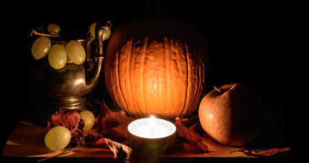 Still life with seasonal fruits, pumpkin illuminated by the light of a candleの写真素材