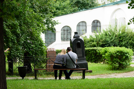 MOSCOW, RUSSIA - AUGUST 14, 2016 - A couple of tourists sitting on a bench in Moscow intent on watching a local guide or your smartphone.のeditorial素材