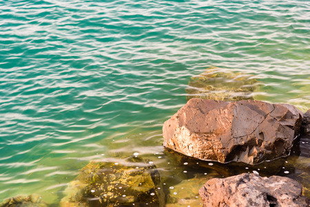 A rock in a turquoise water sea in the small town of Talamone, Italyの写真素材