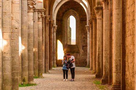 SIENA, ITALY - APRIL 9, 2017 - A couple of guys, look at photos on a side aisle of the Abbey of San Galgano.のeditorial素材