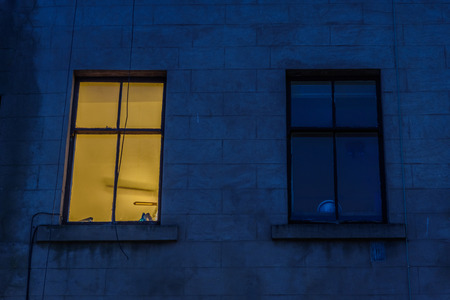 Two windows, one of which is illuminated, on the facade of a building in Scotlandの写真素材