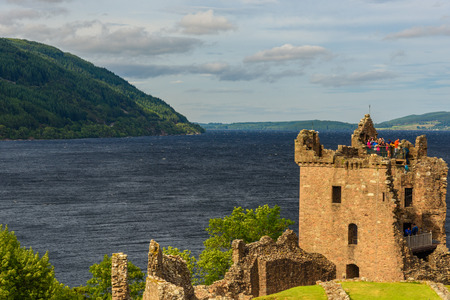 INVERNESS, SCOTLAND - AUGUST 10, 2017 - View of Urquhart Castle in Scotland with a row of visitors exploring castle ruins.のeditorial素材