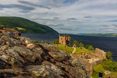 INVERNESS, SCOTLAND - AUGUST 10, 2017 - View of Urquhart Castle in Scotland with a row of visitors exploring castle ruins.の写真素材