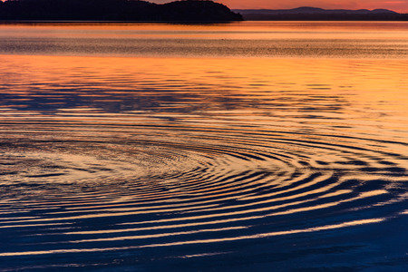 Concentric circles in the water of a lake at sunsetの写真素材