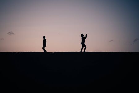 People silhouette against the sky at sunset light on a top of a hillの写真素材