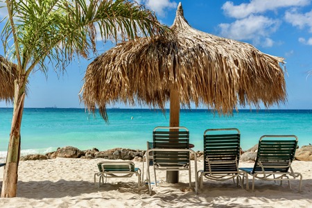 Sunbeds and parasol against the crystal sea water in Eagle Beach, Aruba. Caribbean landscape.の写真素材