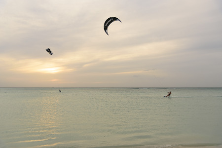 Oranjestad, Aruba - January 16, 2018:A sporty man does acrobatics while practicing kitesurfing at sunset in Aruba.の写真素材
