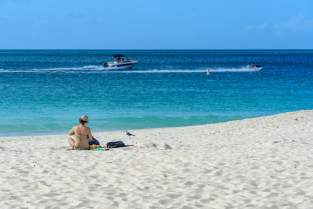 Oranjestad, Aruba - January 13, 2018: A woman relax in the white sand of the idyllic Eagle Beach in Aruba.の写真素材