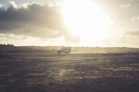 A tourist car against the sun at sunset near the Natural Bridge in Aruba