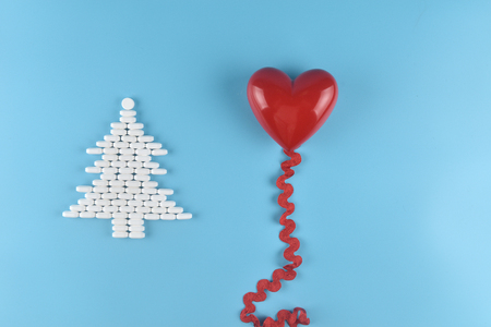 Medicine pills shape of christmas tree and red heart on blue background. Concept christmas and new year.の写真素材